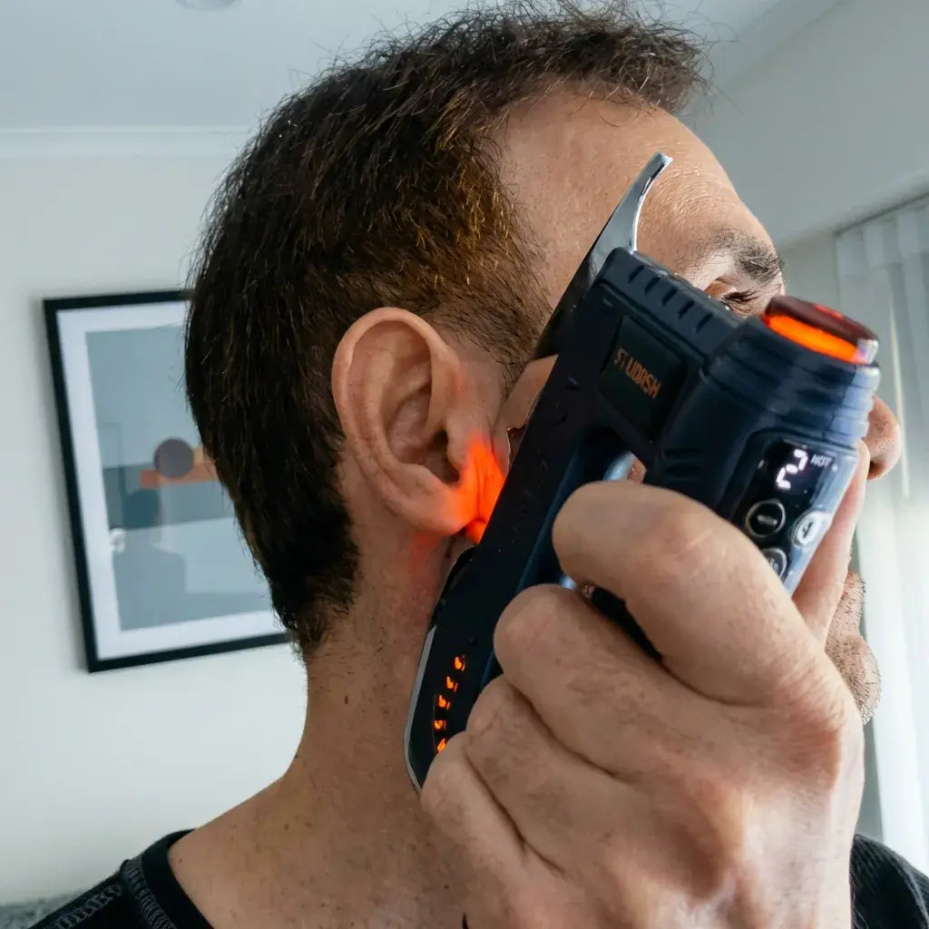 Man using Fitdash Blade Massage Tool near his ear to relieve tension.