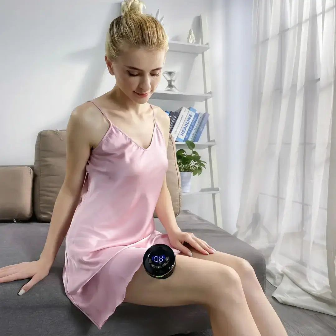 Woman using AcheFly Smart Cupping Device on her thigh while sitting on a couch in a bright room.