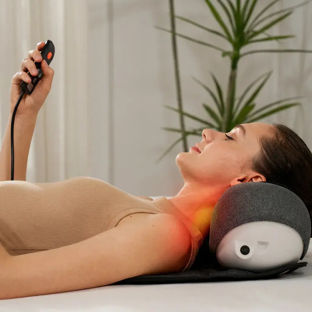 Woman relaxing with the CerviCloud Neck Stretch Pillow while using its remote control.