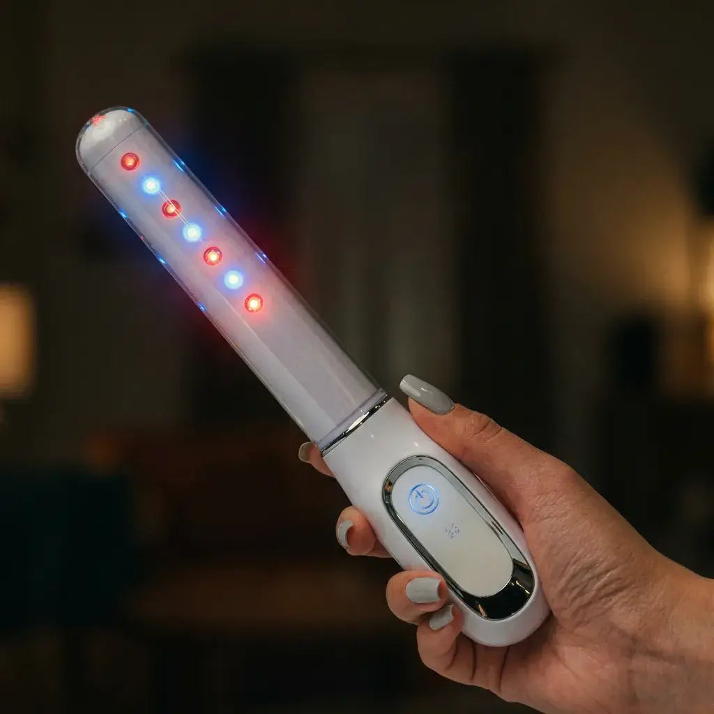 Person holding the Femniva Wellness Wand with colorful LED lights glowing.