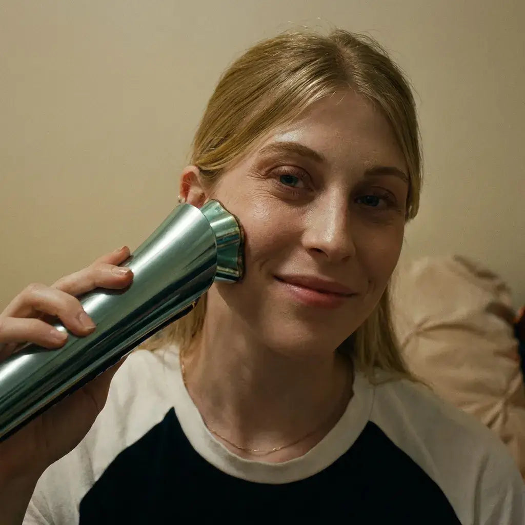 A woman using the Polaris-II Advanced Beauty Device on her face, smiling in a cozy setting.