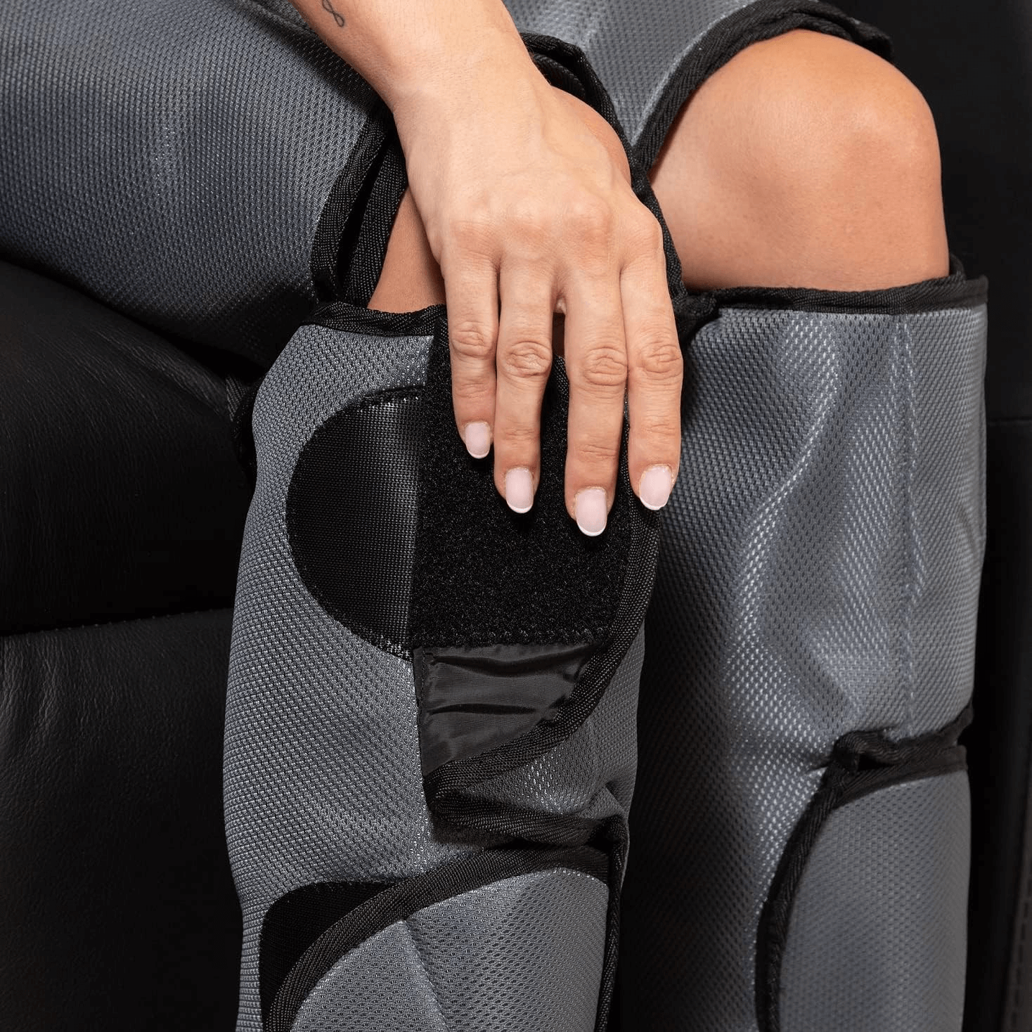 Close-up of a hand adjusting the Comprax Air Boots on a seated person's leg.