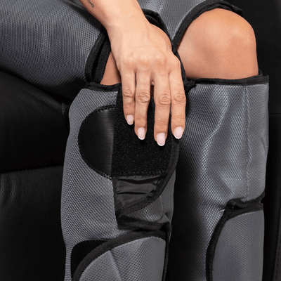Close-up of a hand adjusting the Comprax Air Boots on a seated person's leg.