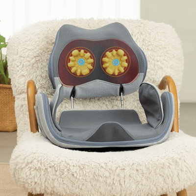 Hipology Massage Seat positioned on a cozy chair, showcasing its therapeutic design with kneading rollers.