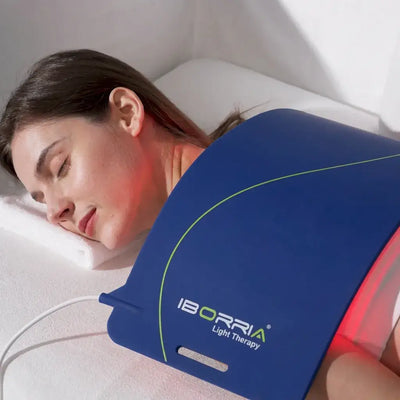 A woman relaxing with the LumiCura Flexible Light Panel positioned on her back during light therapy.