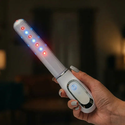 Person holding the Femniva Wellness Wand with colorful LED lights glowing.