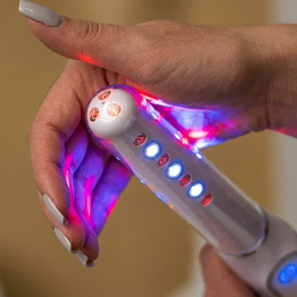 Close-up of a hand holding the Femniva Wellness Wand, showcasing its light features and ergonomic design.