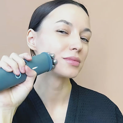 A woman using the Vellura-Gess Contour & Renew device on her face, showcasing its elegant design.